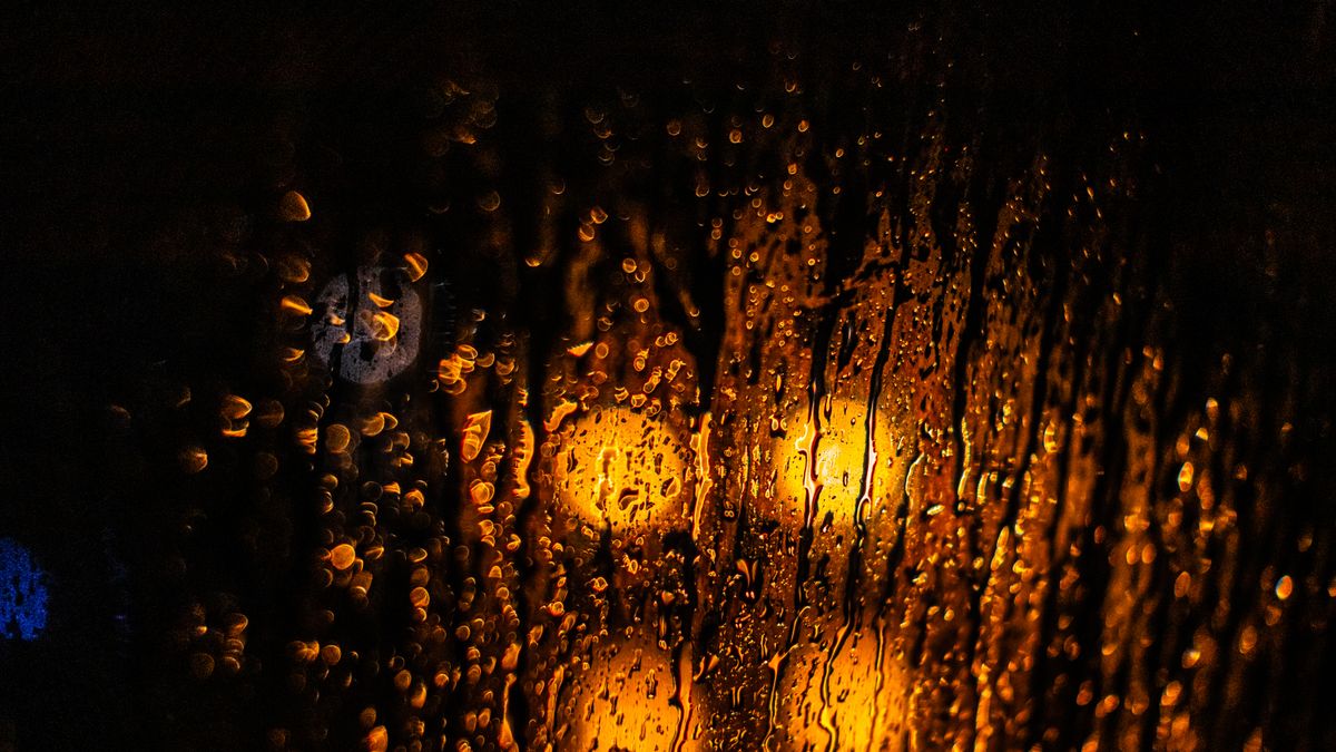 Gotas de lluvia en un cristal con las luces calidas de la calle desenfocadas detras