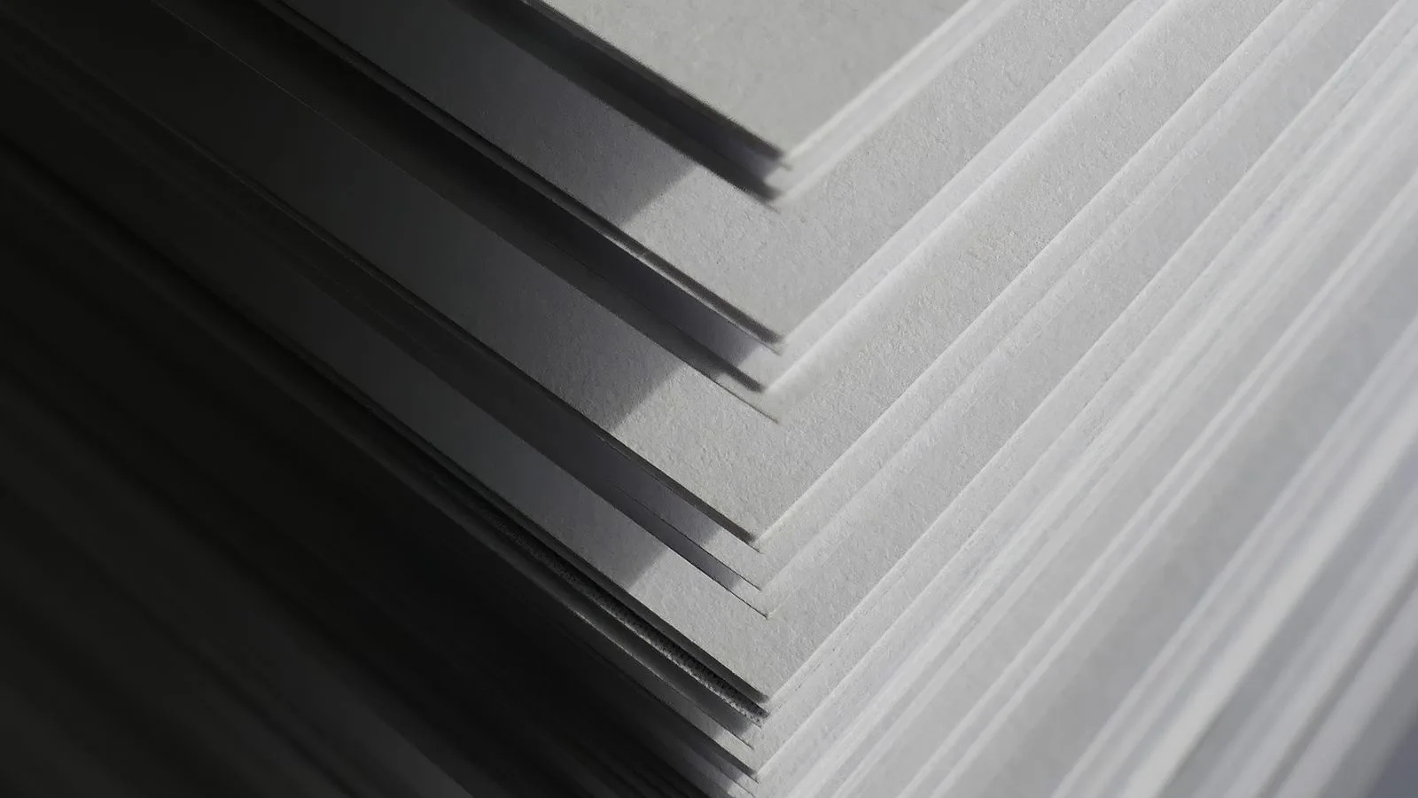 Hojas de papel apiladas con sombras marcadas, vistas de cerca