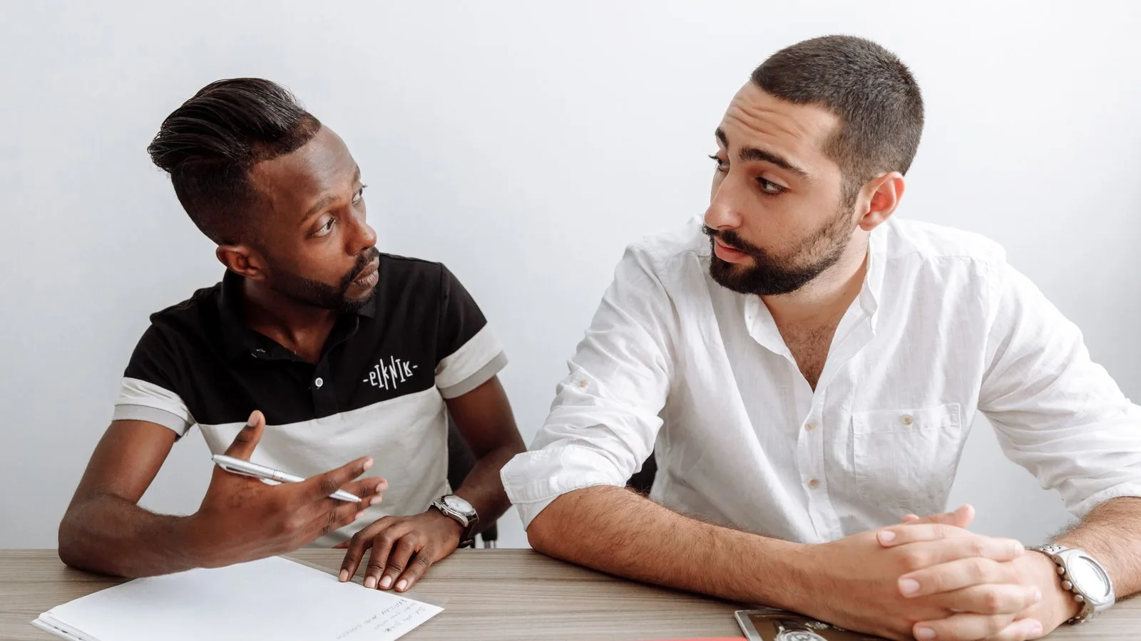 Dos personas conversando de frente a un lado y otro de un escritorio