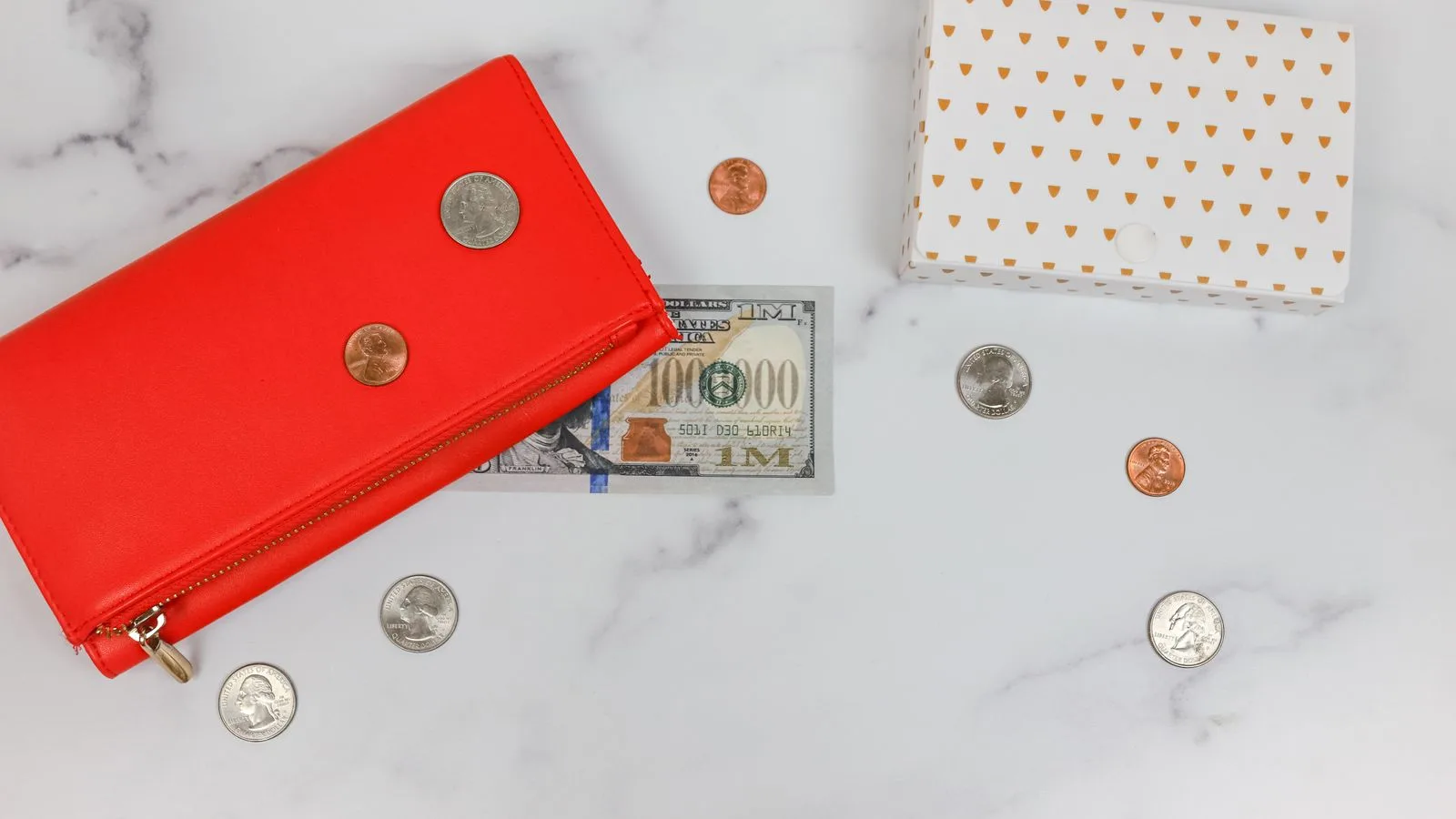 Una alcancía, una cartera roja y billetes vistos desde arriba sobre mármol
