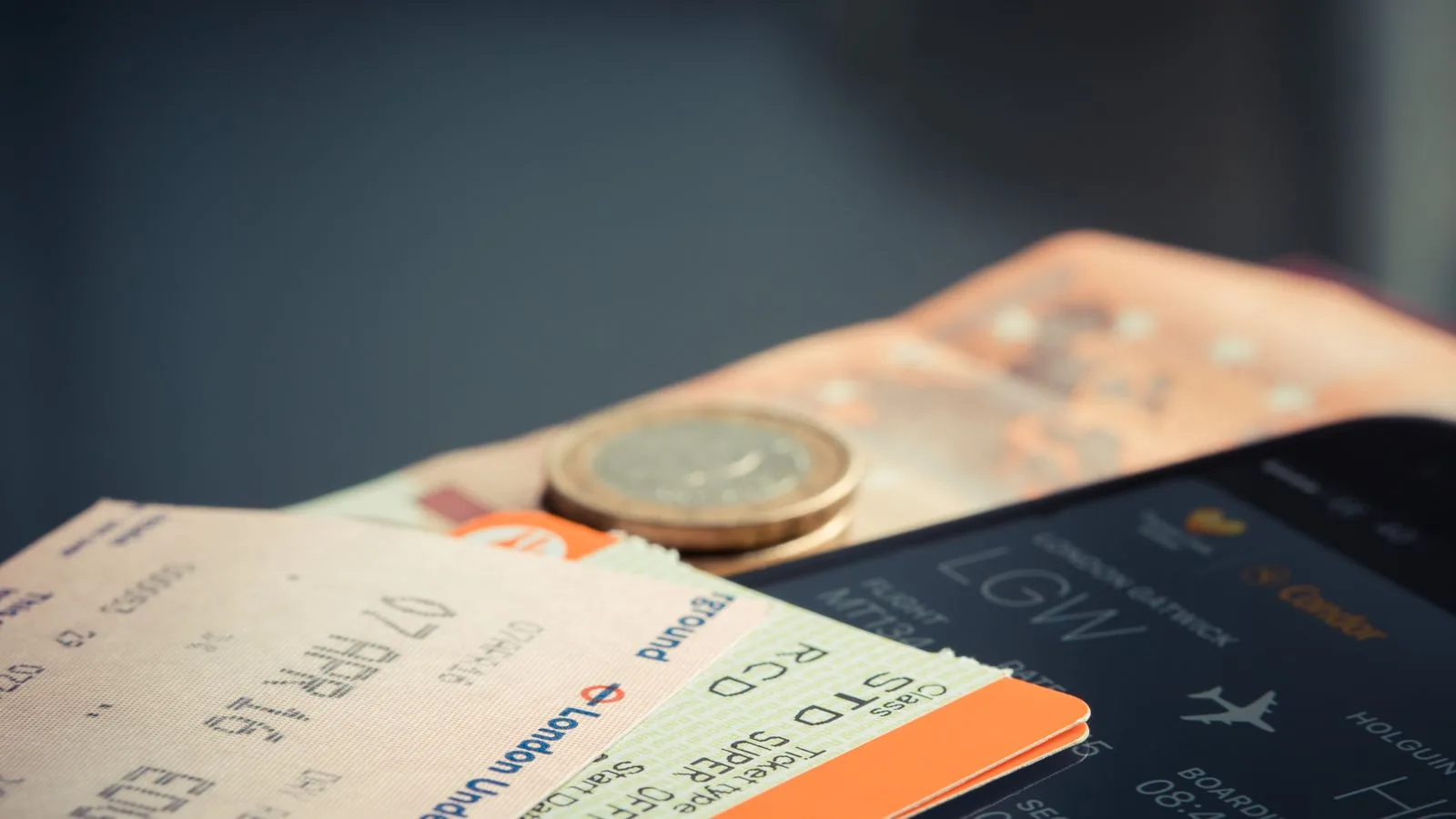 Monedas sueltas y tickets de compra sobre una mesa oscura