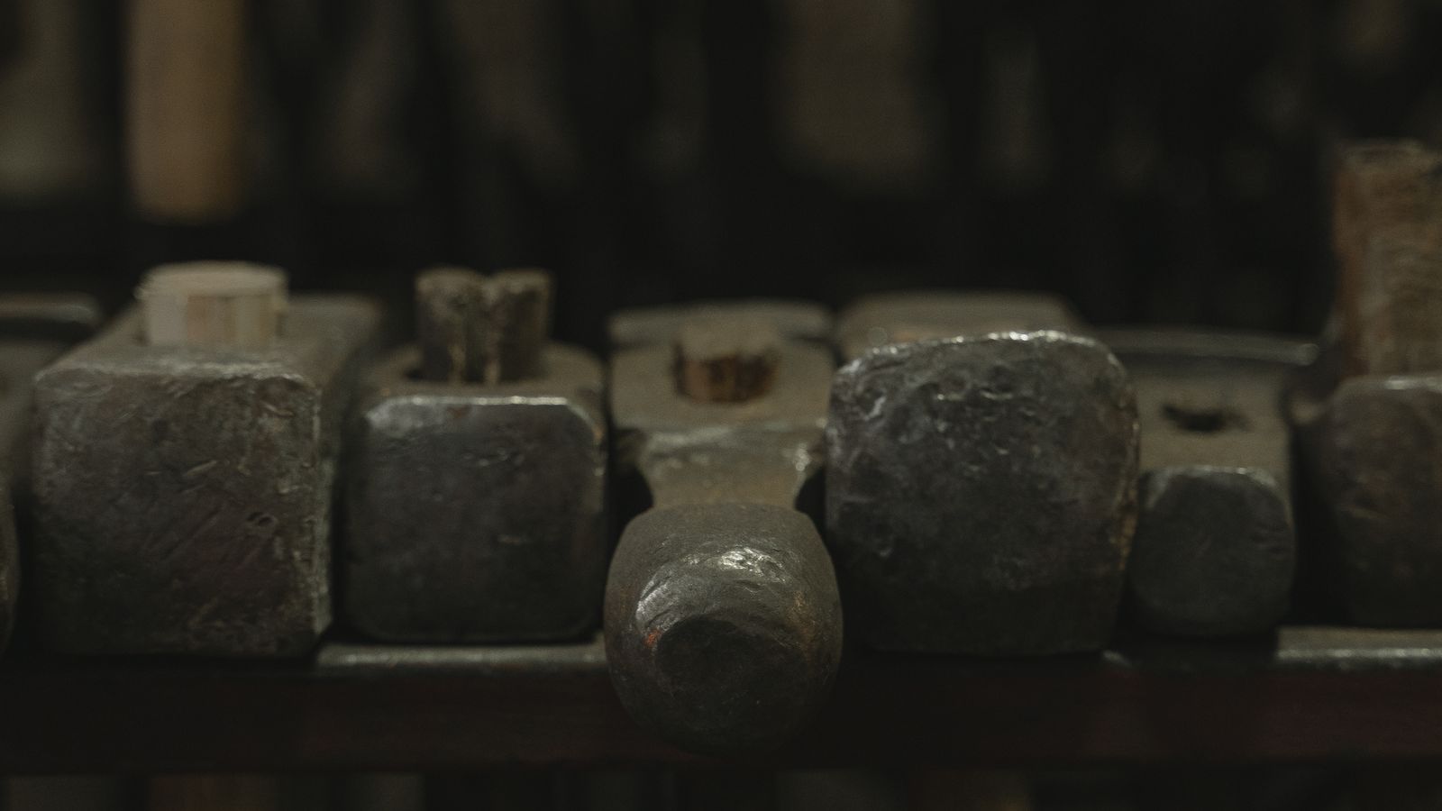 Cabezas de martillo alineadas en un estante de taller en penumbra
