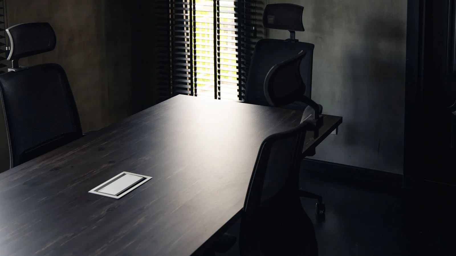 Una mesa de juntas vacía en una sala en penumbra