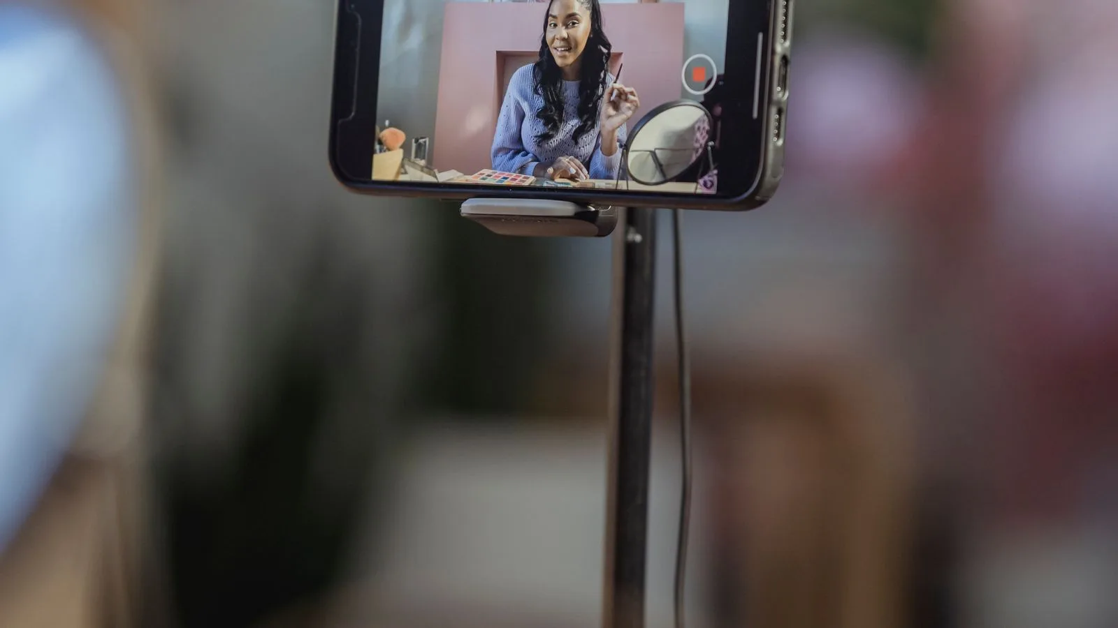 Un telefono montado en un tripode grabando a una persona, con el fondo a oscuras