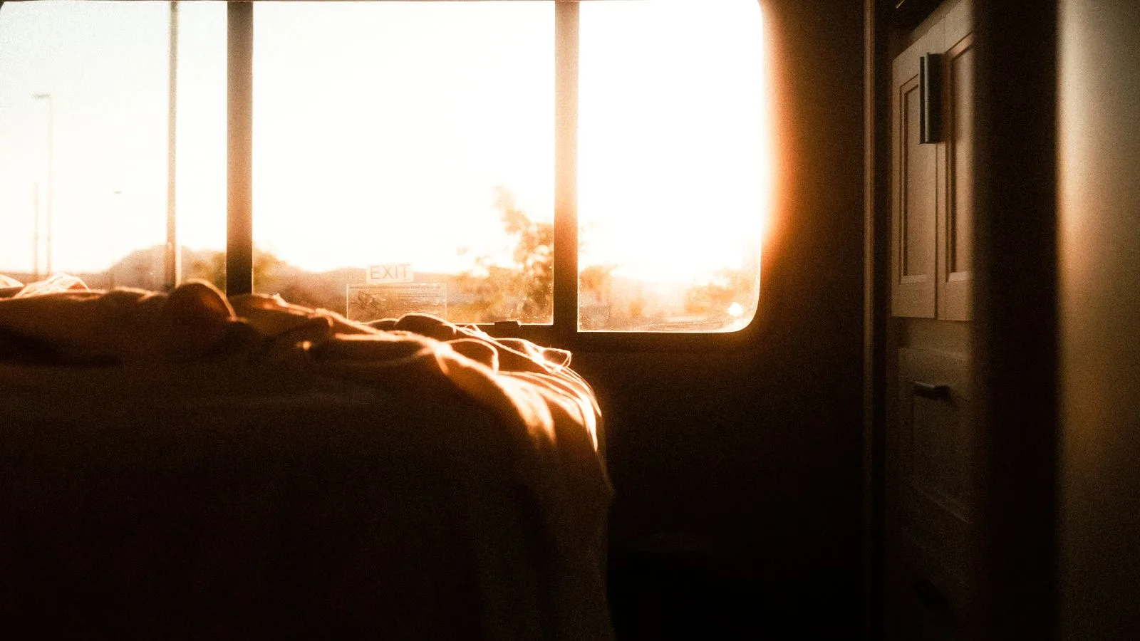 Una habitación a oscuras con la primera luz del día entrando por la ventana