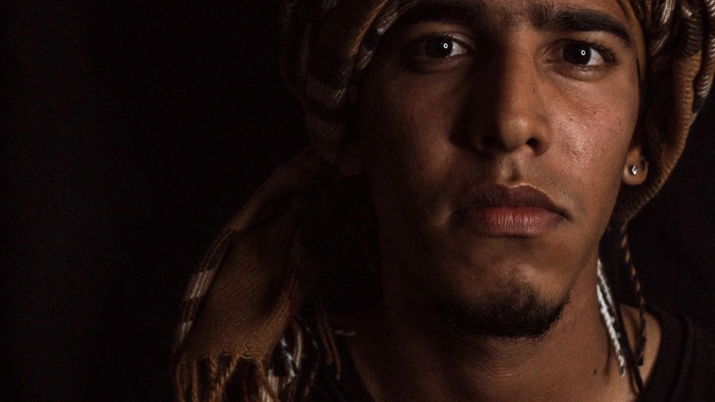 Retrato de un hombre joven mirando de frente, con luz lateral en penumbra
