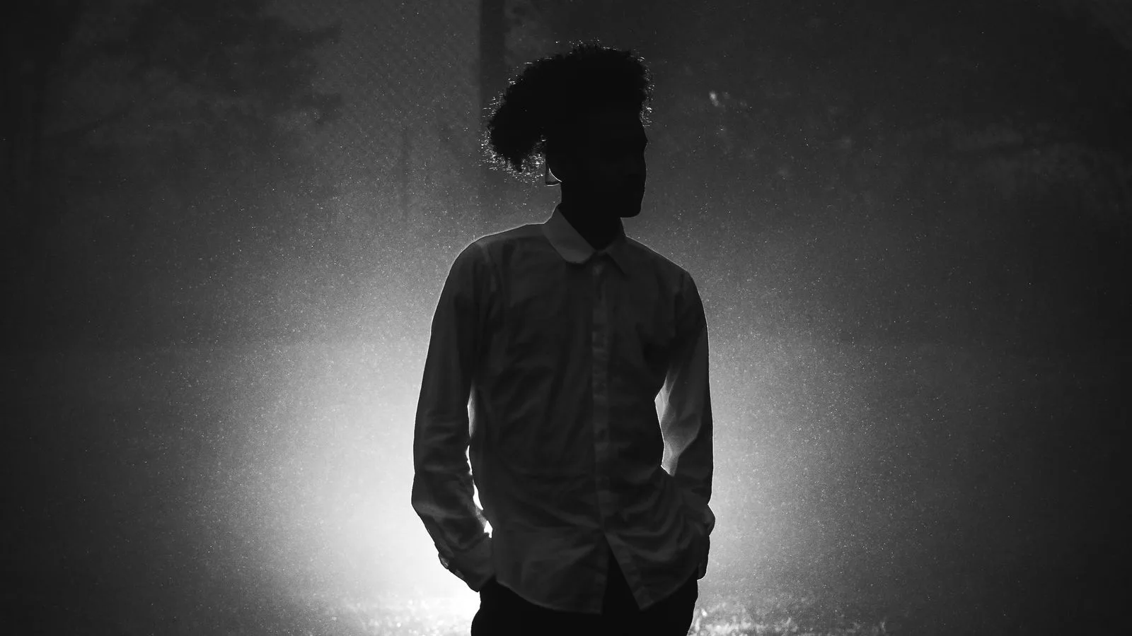 La silueta de una persona de pie entre la niebla, en blanco y negro