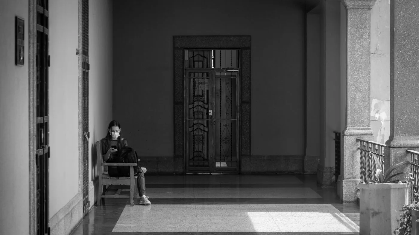 Una persona esperando sola, sentada al fondo de un pasillo vacío