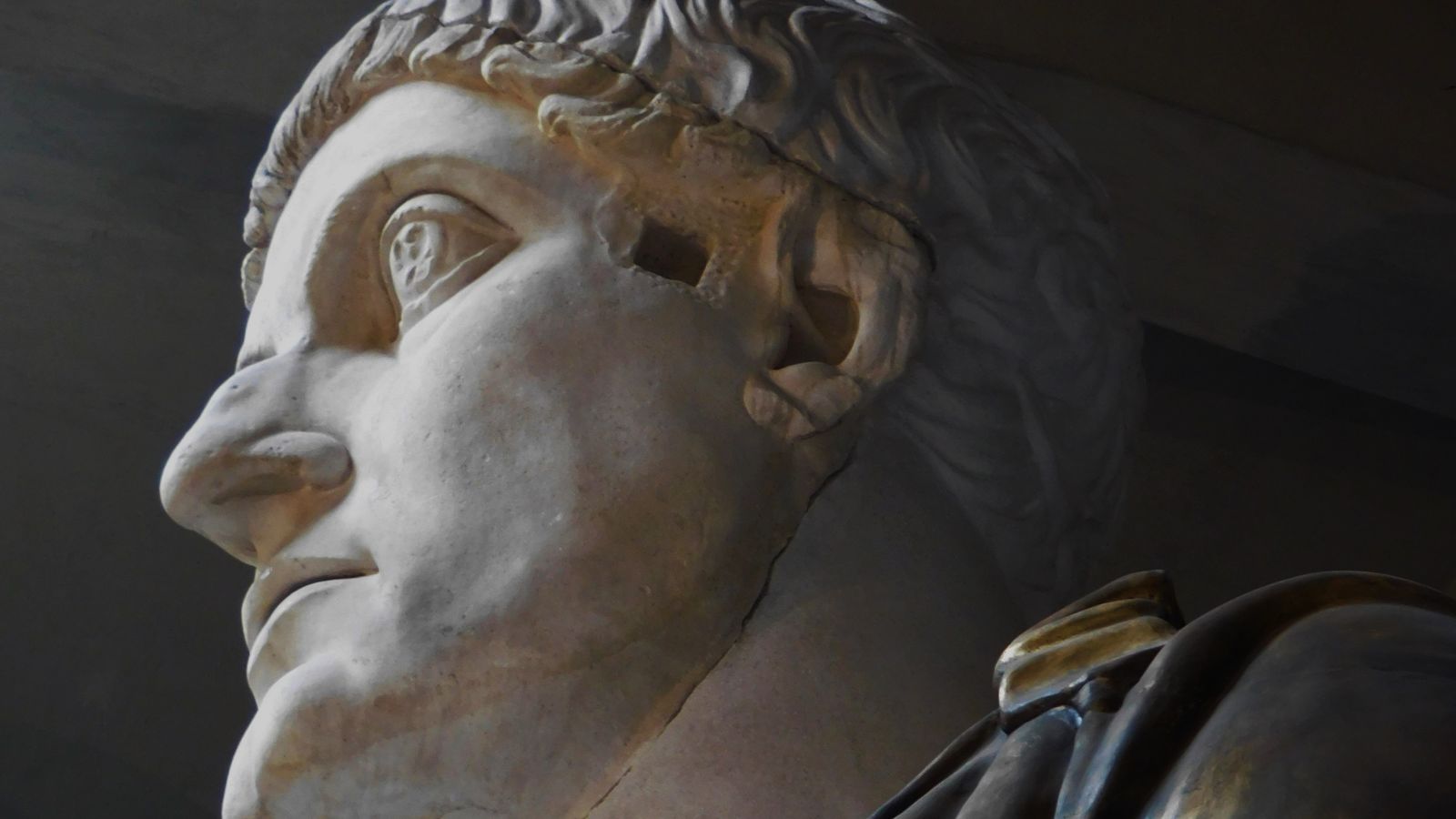 Un busto de mármol romano de perfil, iluminado sobre fondo oscuro