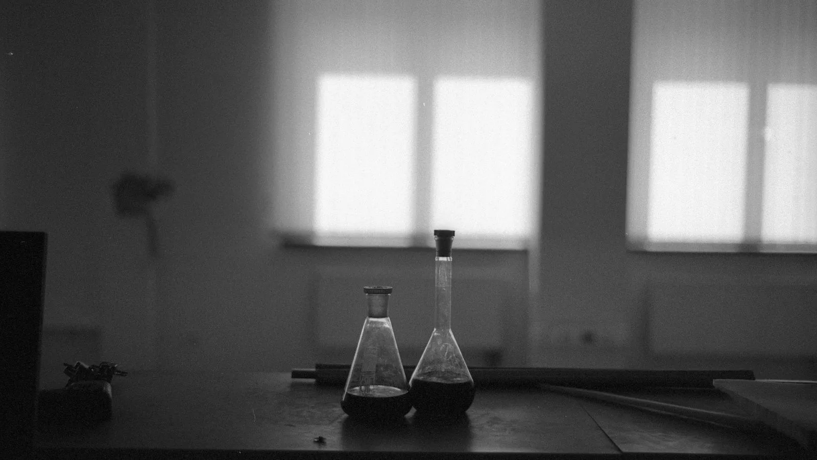 Viales de laboratorio en blanco y negro, junto a una ventana
