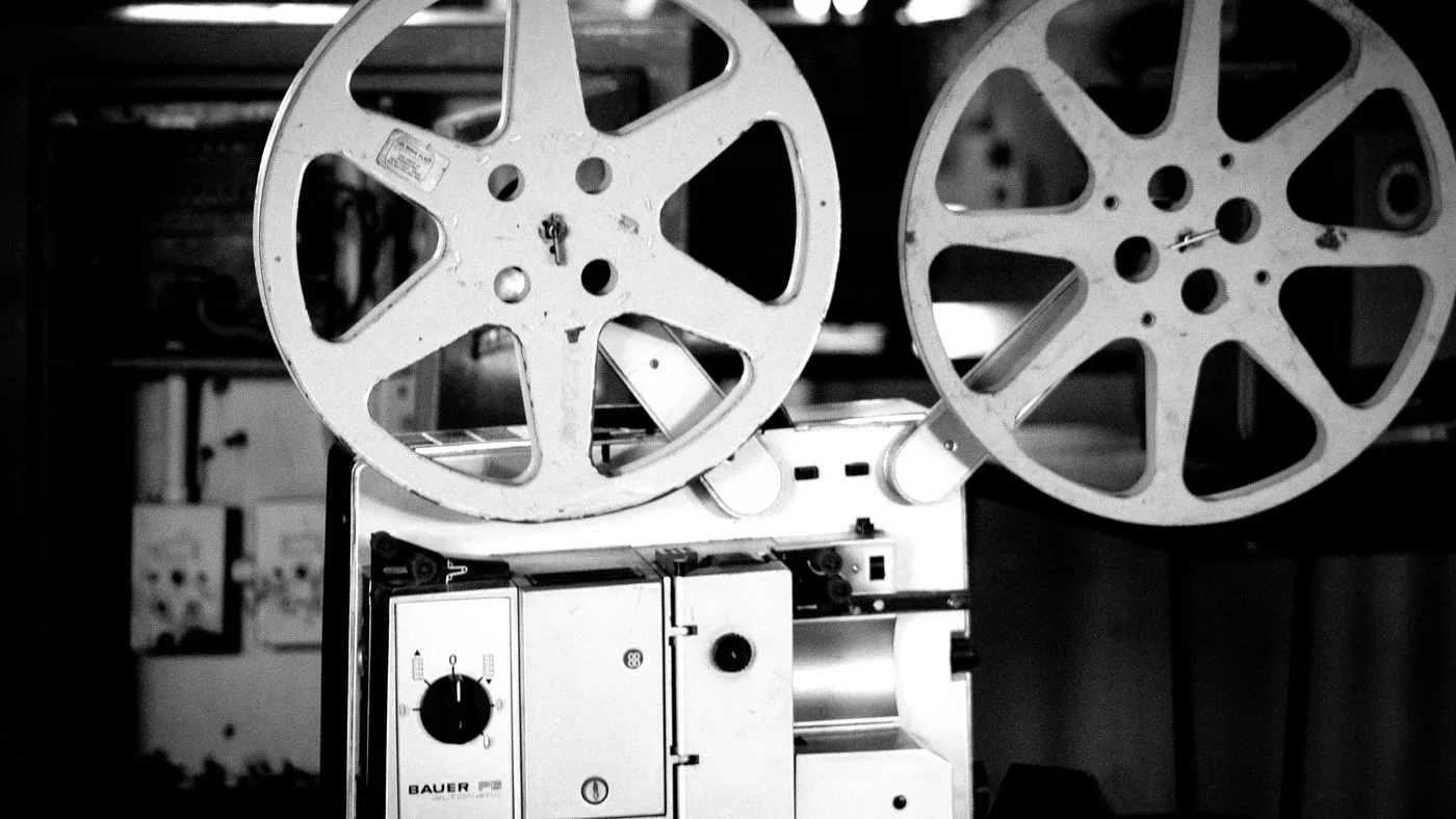 Un proyector de cine de época con sus rollos, en blanco y negro