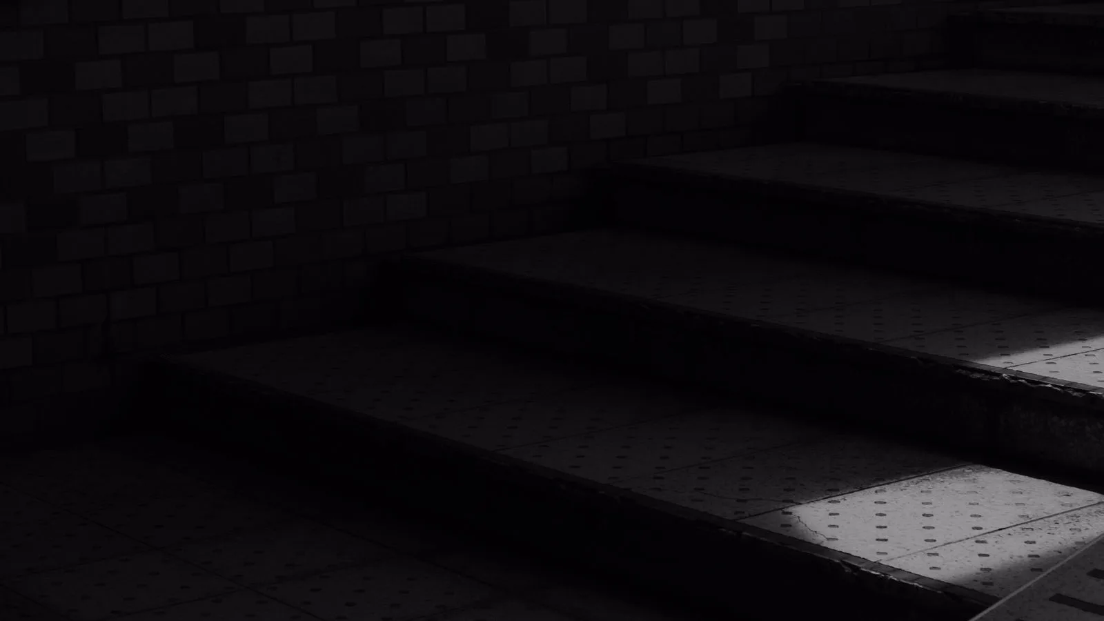 Una escalera vista desde abajo, en blanco y negro, con sombras marcadas