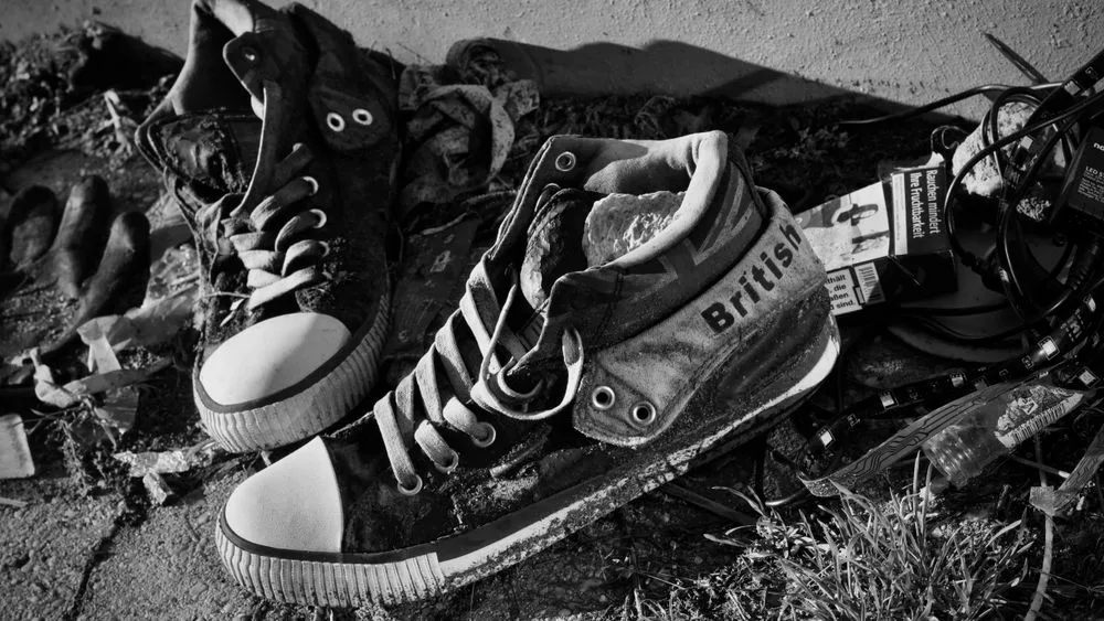 Un par de zapatillas gastadas sobre un suelo oscuro