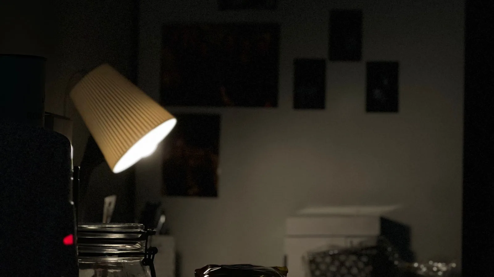 Un escritorio en penumbra iluminado solo por una lámpara, con apuntes encima