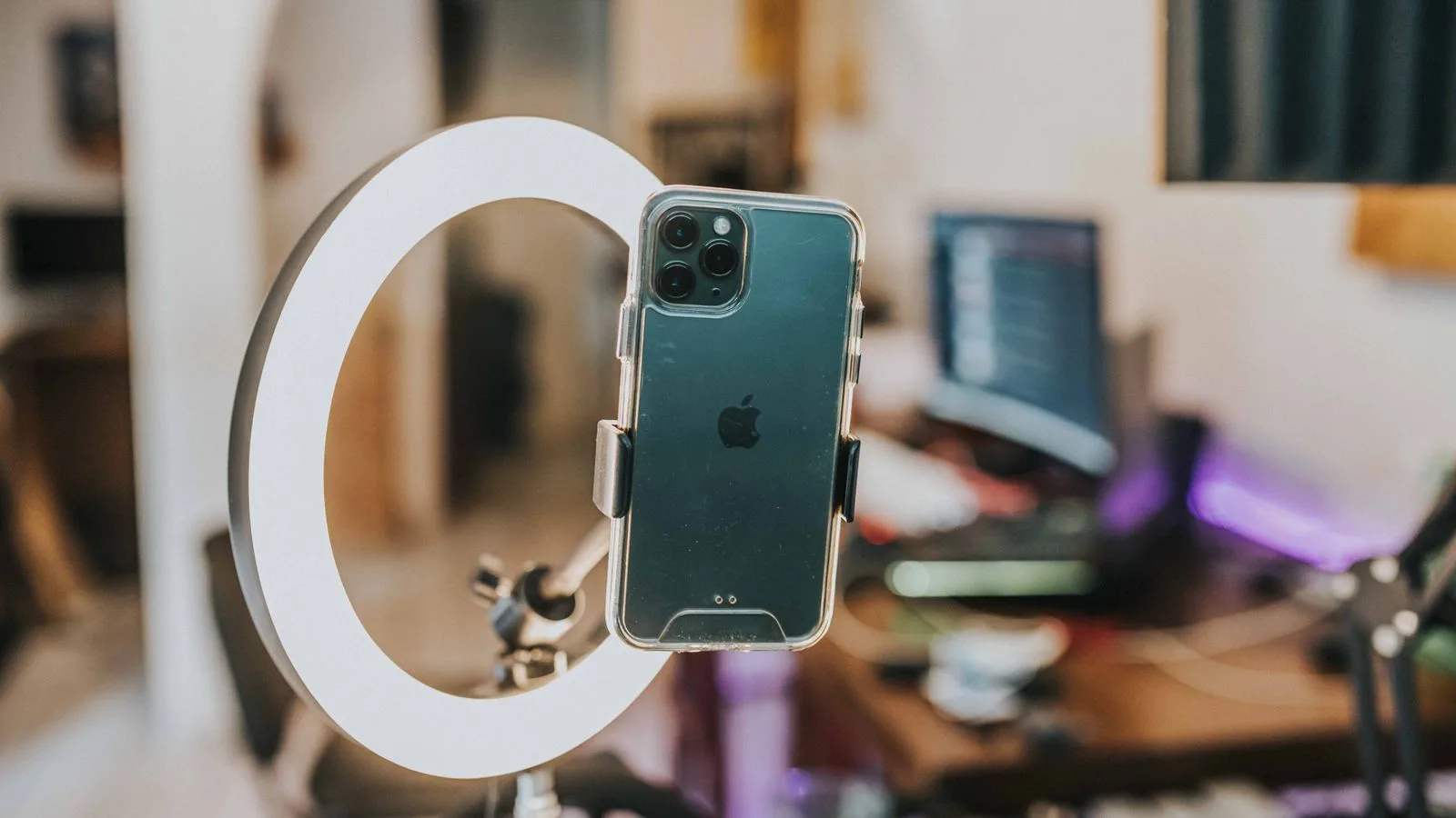 Un teléfono montado en un aro de luz, listo para grabar video en un escritorio