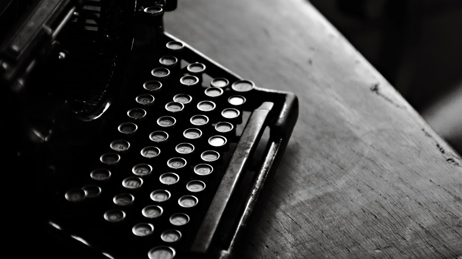 Una máquina de escribir antigua en blanco y negro sobre un escritorio de madera