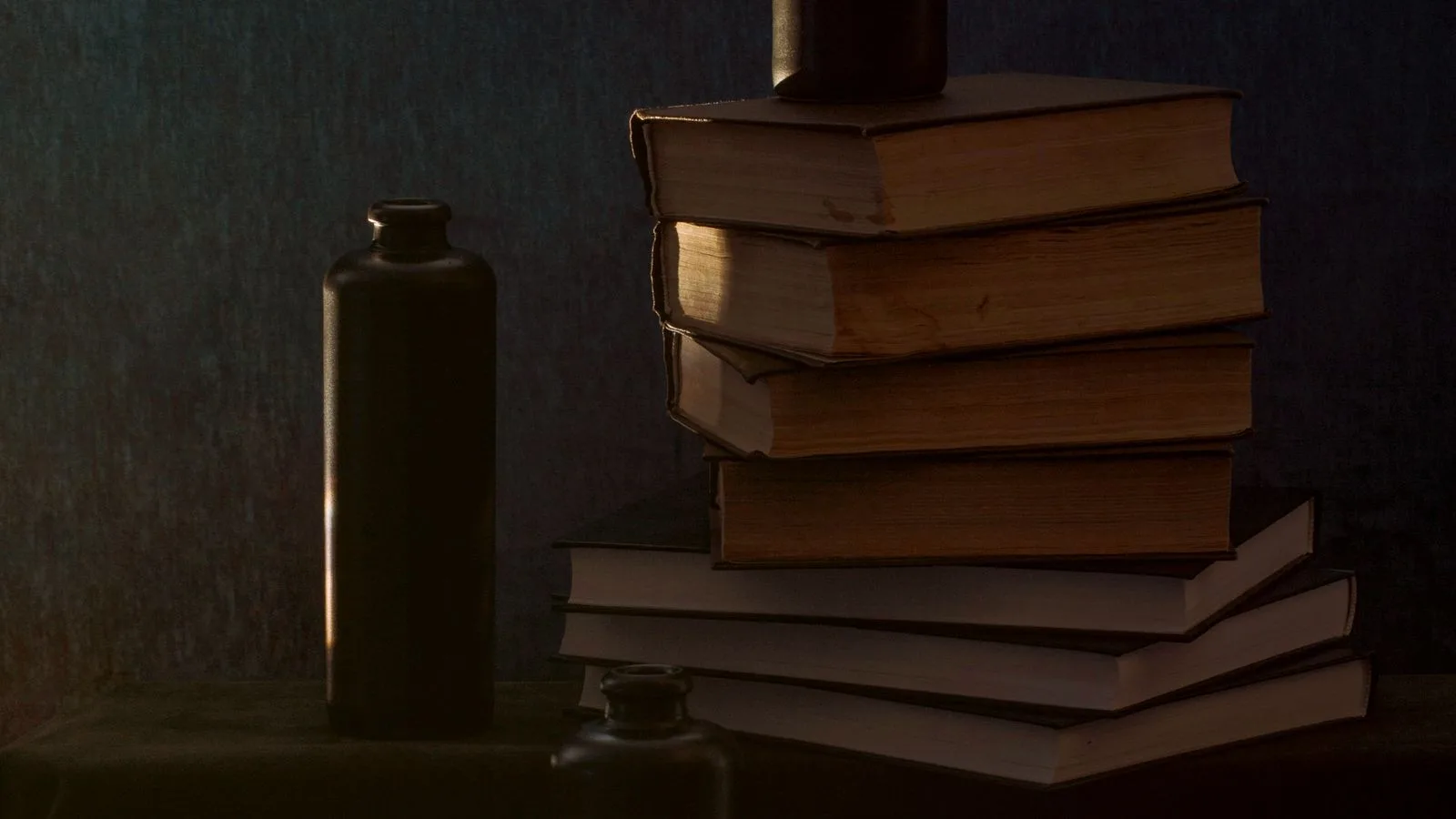 Una pila de libros antiguos con luz cálida sobre fondo oscuro