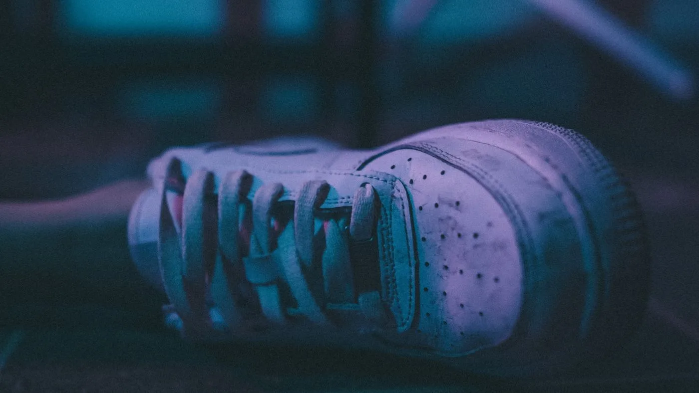 Una zapatilla deportiva en el suelo de una habitación poco iluminada