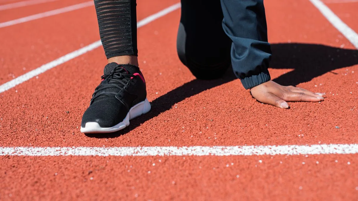 Una corredora en posición de salida sobre la pista de atletismo