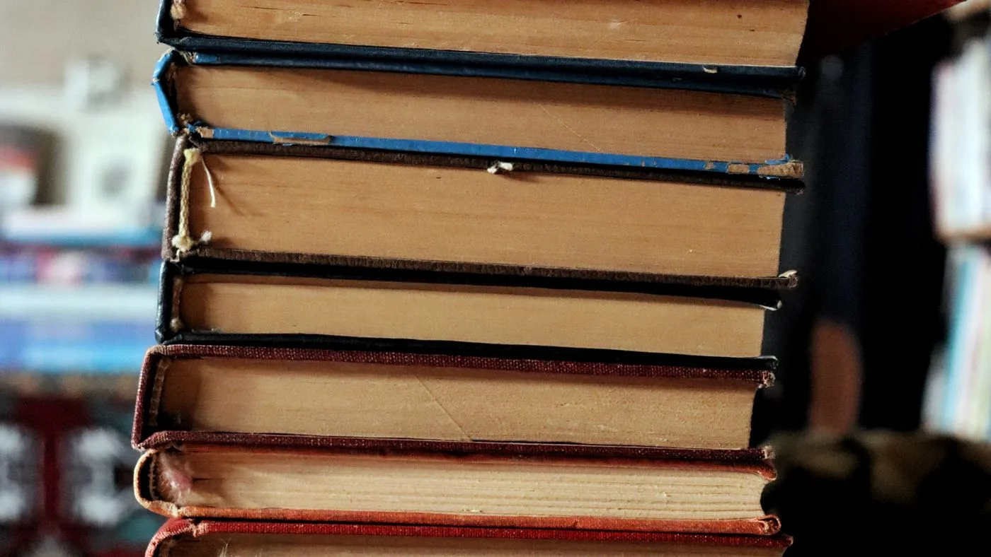 Una pila alta de libros gastados, vistos de cerca por el canto