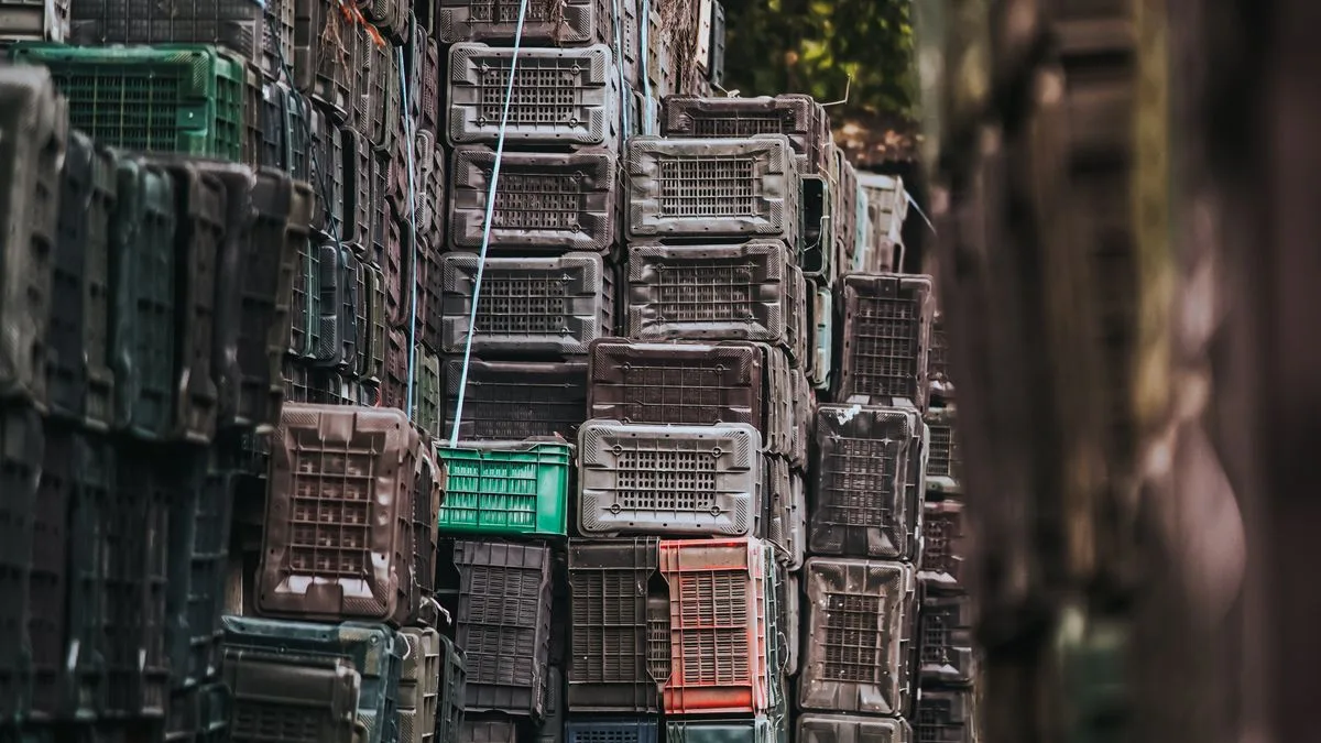 Un callejón estrecho abarrotado de cajas apiladas hasta arriba, perdiéndose en la penumbra