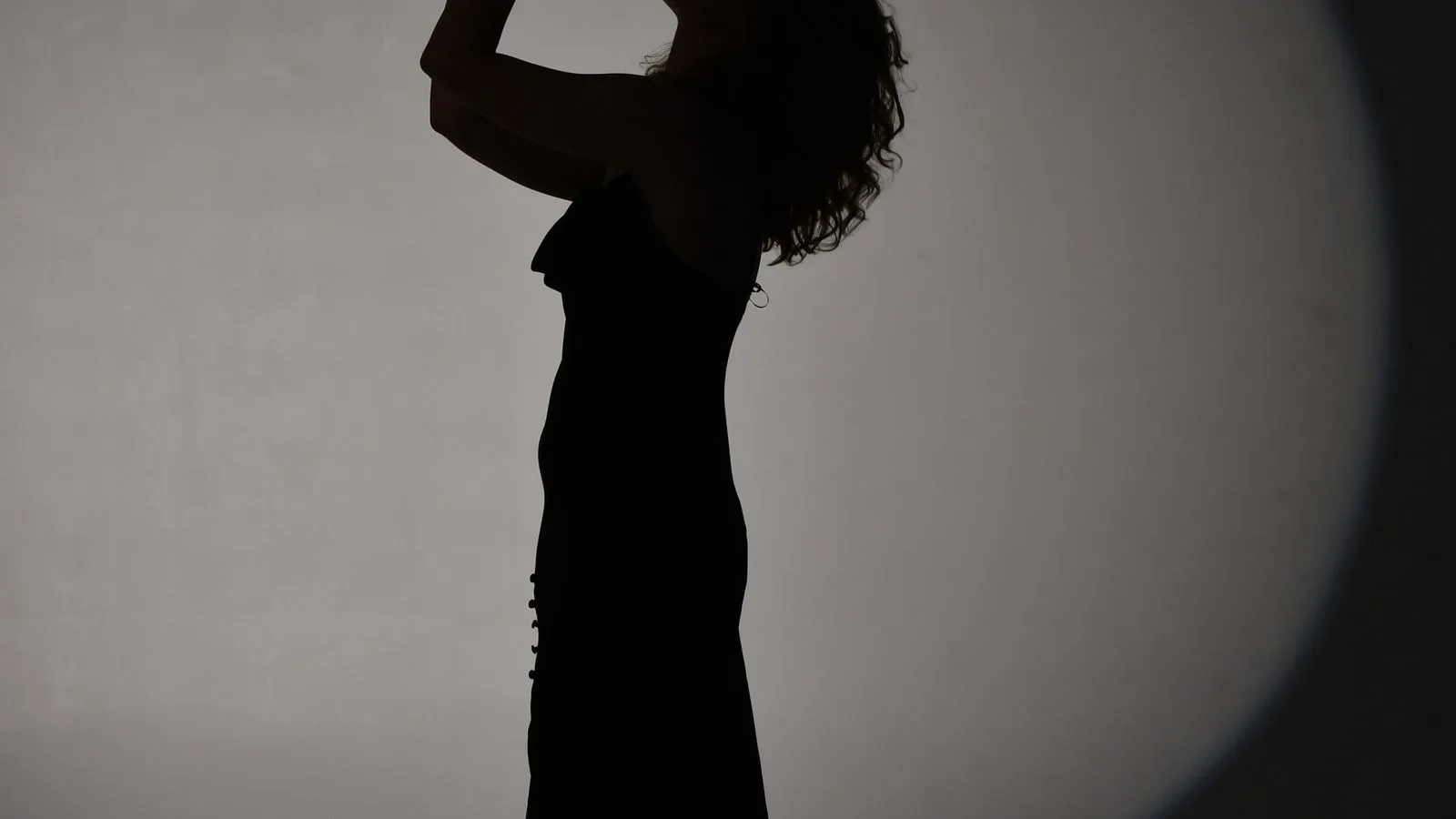 La silueta de una mujer hablando, recortada contra un foco de luz