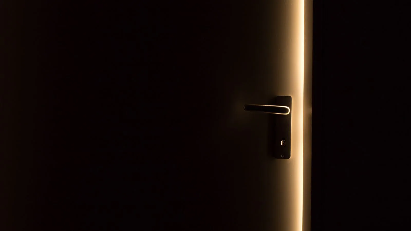 Una puerta entreabierta con una línea de luz cálida al fondo