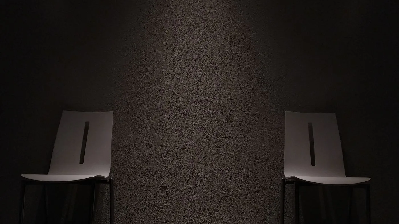 Dos sillas separadas frente a una pared oscura
