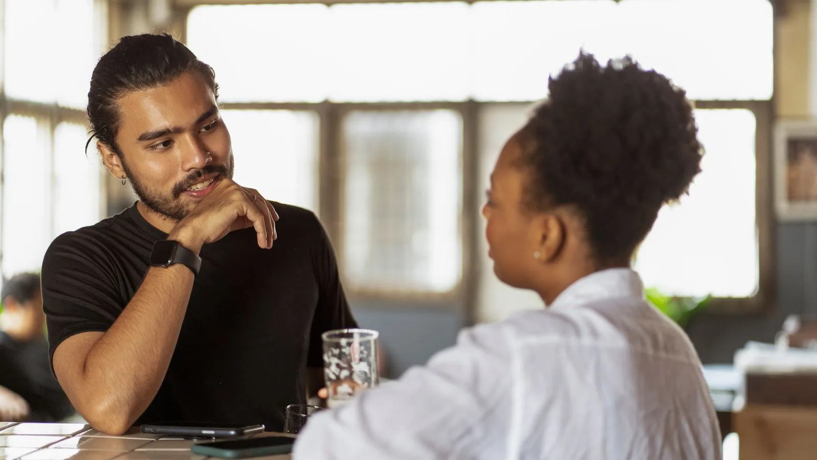 Dos personas conversando de frente en una mesa, escuchándose